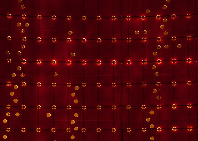 Grid of warm white lights reflecting from a red steel w ...