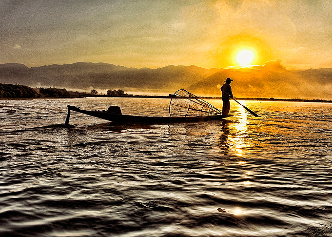 Fisherman on boat under sunset with paint effect