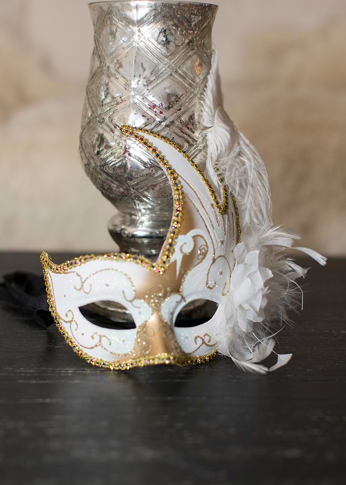 Mardi Gras mask with silver urn candle holder on my bla ...