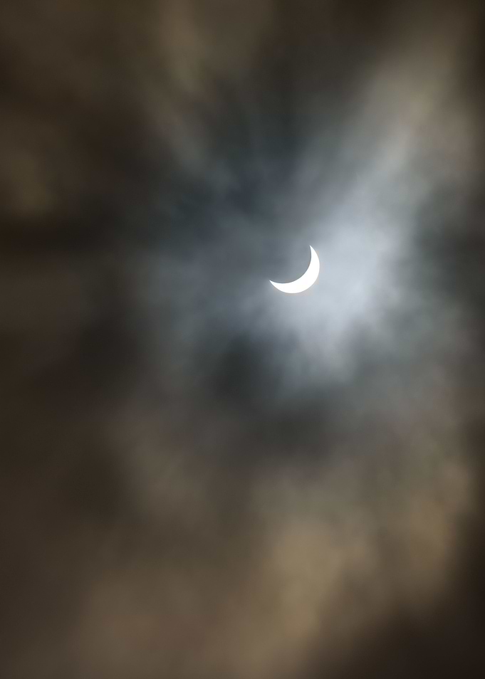 Partial solar eclipse with clouds, the moon passes betw ...