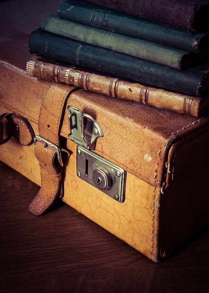 Still life with an old suitcase and pile of books