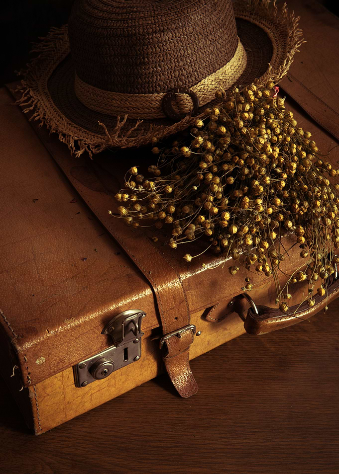 Still life with straw hat and leather suitcase