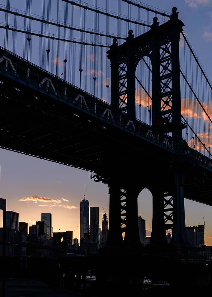 The Manhattan Bridge and the skyline are silhouetted on ...