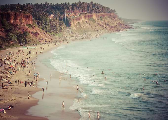 Sunbathers and swimmers gather on the beach below the c ...