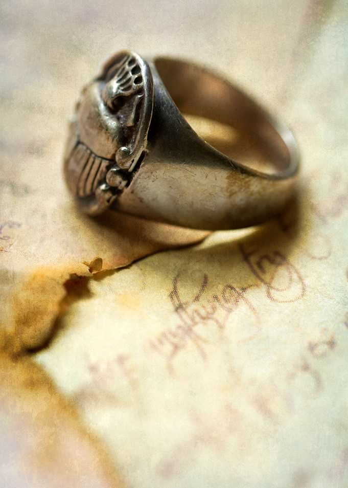 Still life with silver ring and burnt letters