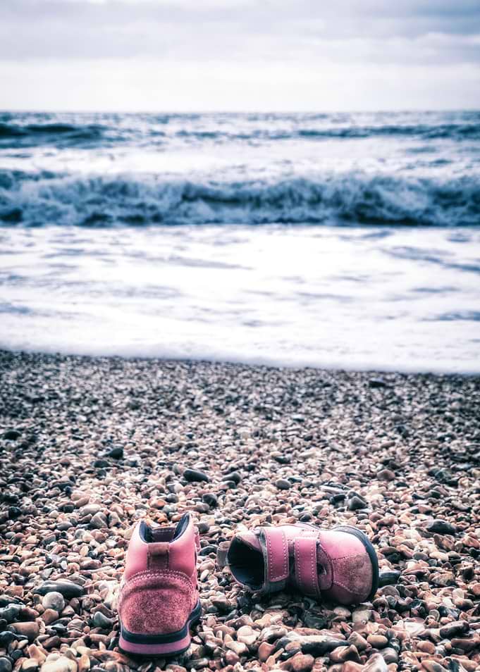 pink children's shoes at the beach