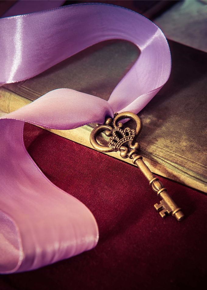 Still life with ornamented brass key and violet ribbon