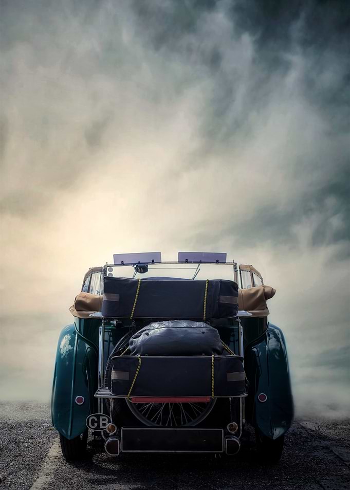a classic car with suitcases and bag