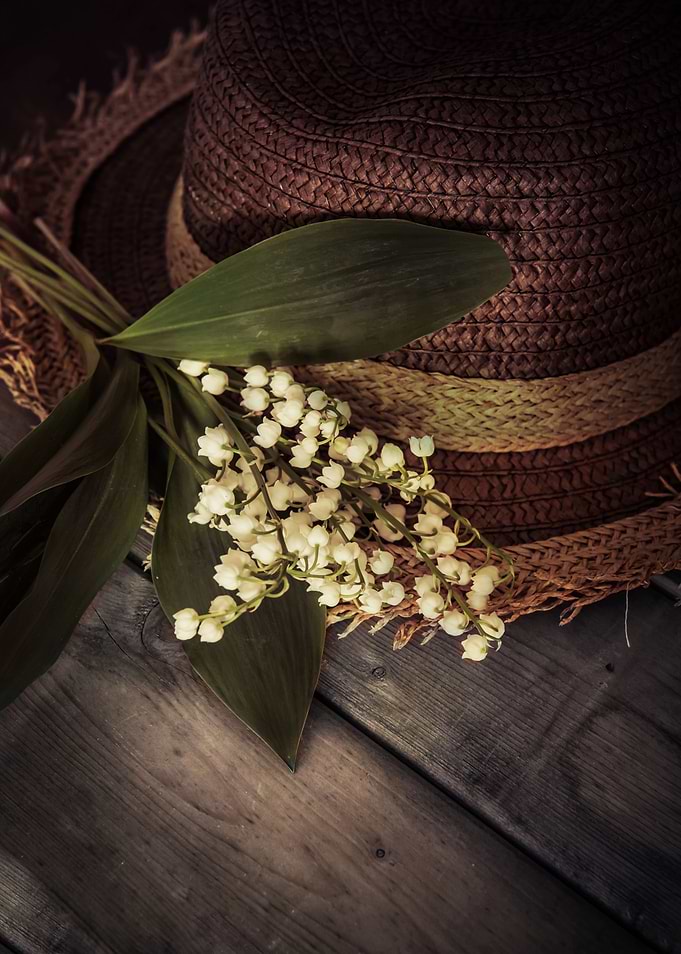 Old straw hat and bouquet of lilly of the valley flower ...
