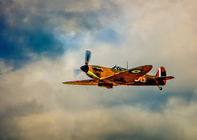 WWII fighter plane flying through cloudy skies over the ...