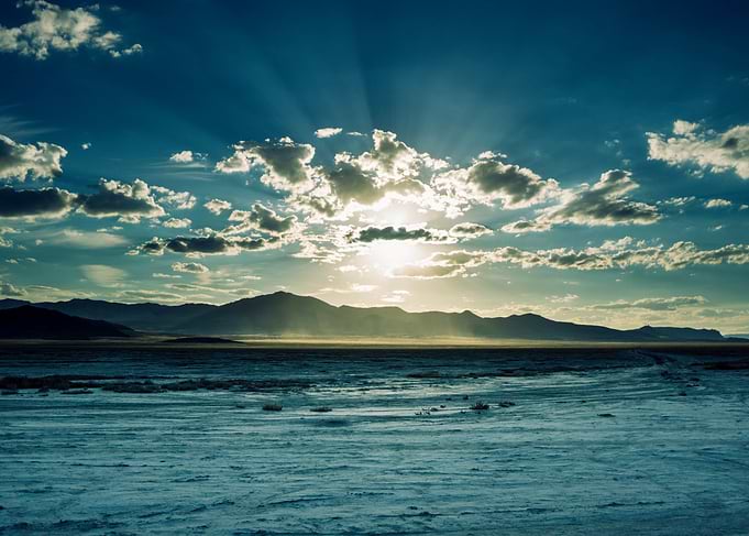 The sun sets behind the mountains in the desert.