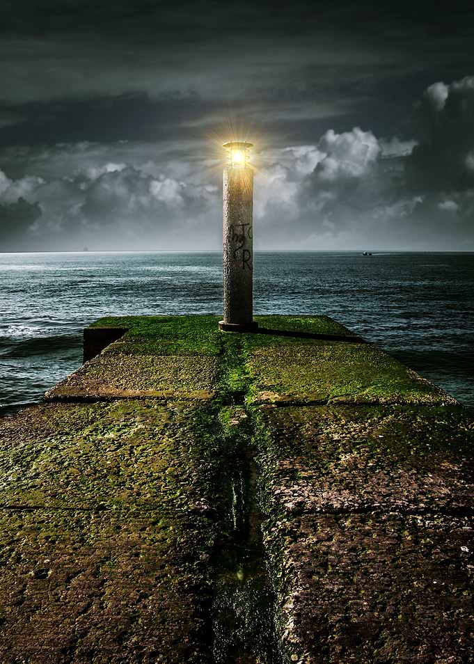 Pier with naval navigation light sign under a stormy sk ...