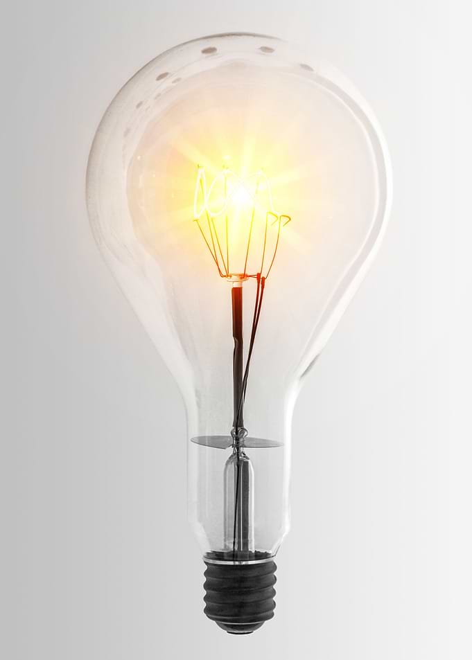 Old lamp with light beam on filament over white backgro ...