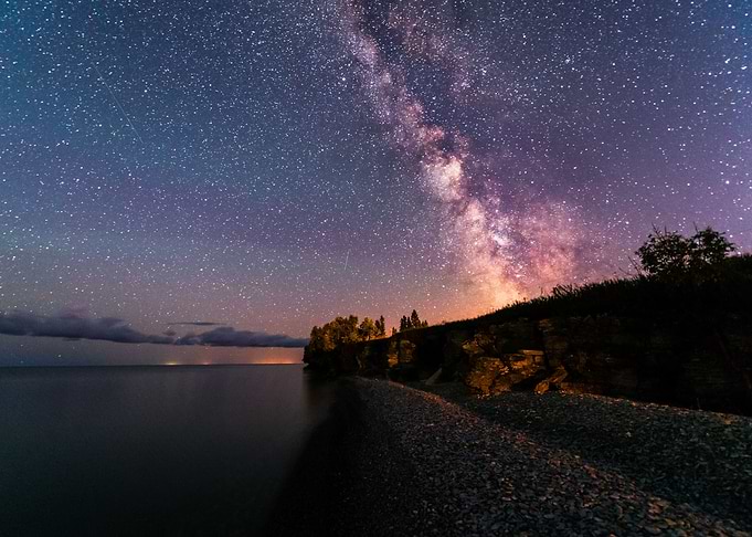 Milky way rising above rocky beach