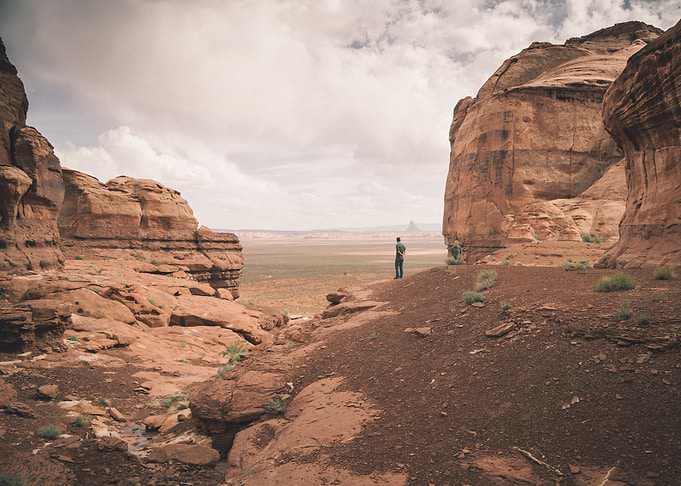 A man stands thoughtfully on a bluff looking over the d ...