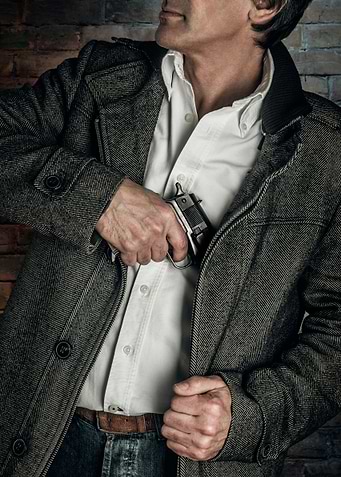 Torso of a man drawing a handgun from inside his coat