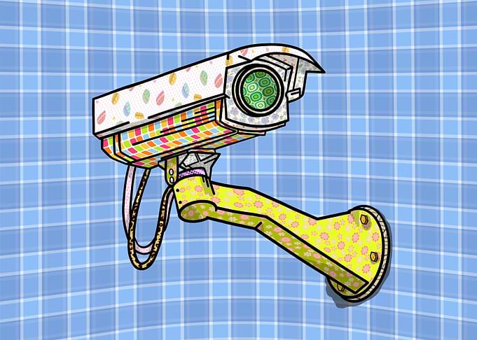 A security camera attached to a blue plaid wall. The ca ...