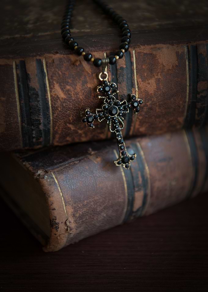 Black cross pendant and old books