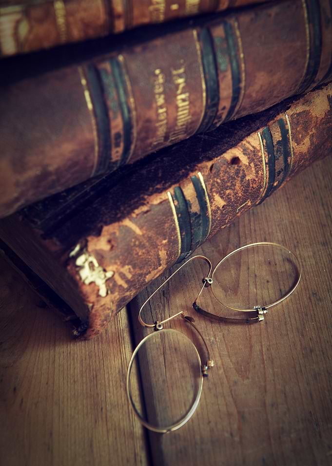 Pile of old books and vintage glasses