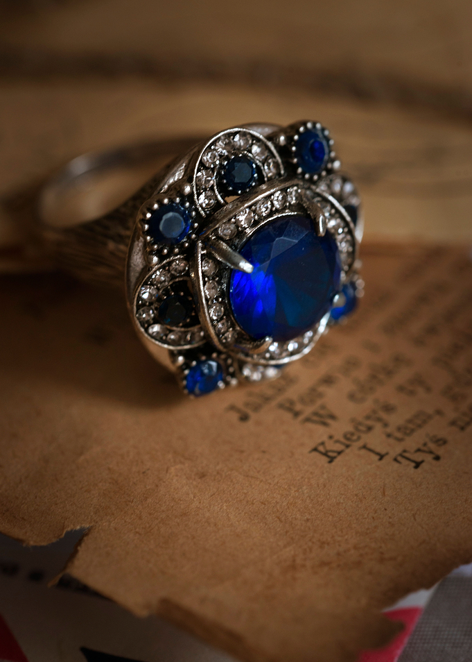 Nice detailed ring with blue gem on torn pages with tex ...