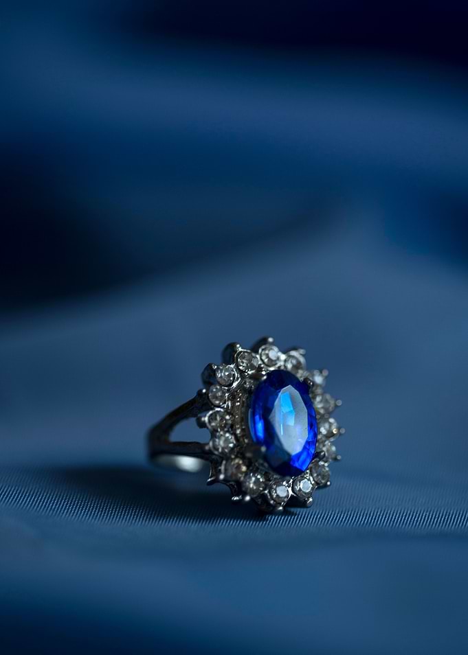 Small silver ring with blue gem on blue fabric