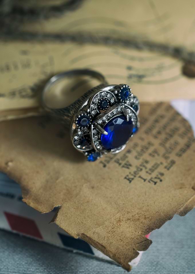 Big ornamented ring with blue gem on old letters and en ...