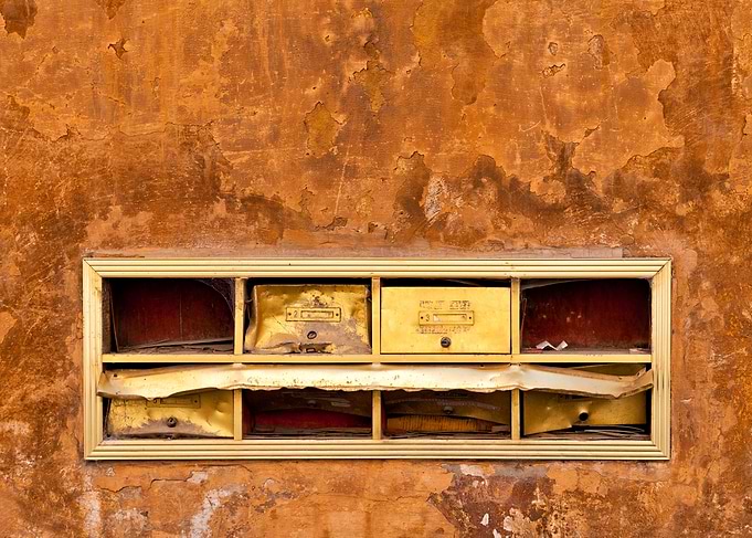 Abandoned and old mailboxes at old plaster wall with cr ...