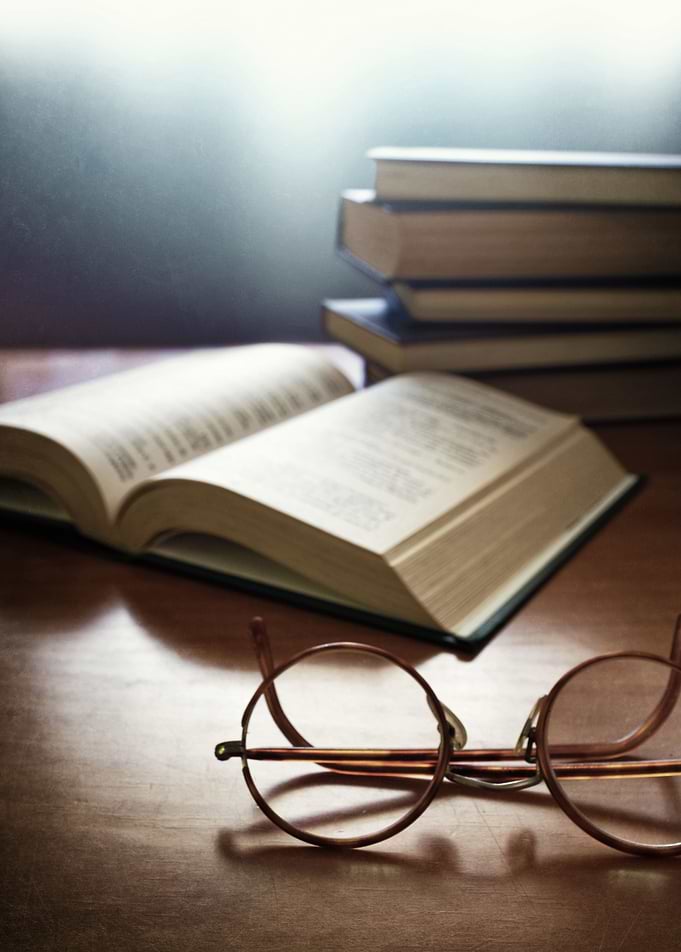 Pile of old books and a pair of vintage glasses