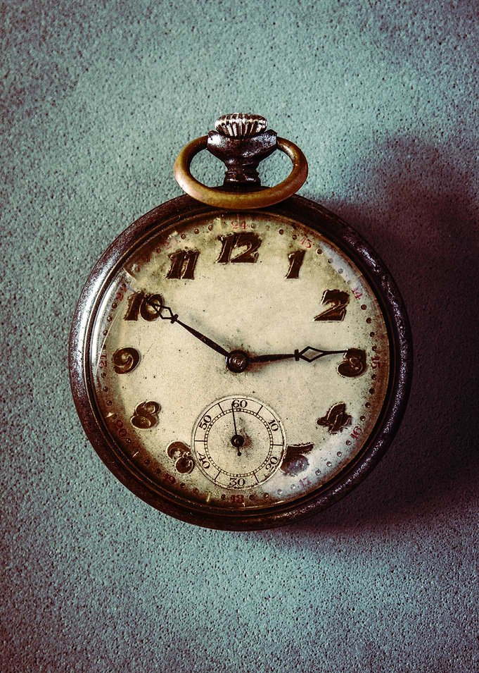 Old worn pocket watch over a textured surface.