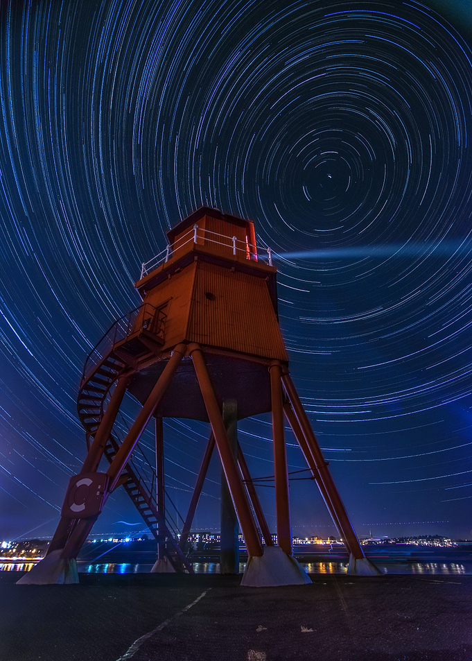the movement of the stars under a lighthouse shining ou ...