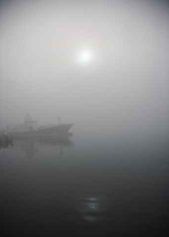 The sun peeking through the fog by the harbor in Tromsø ...