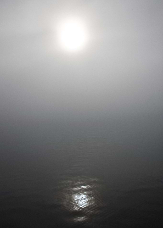 The sun peeking through the fog. Dimmed version.