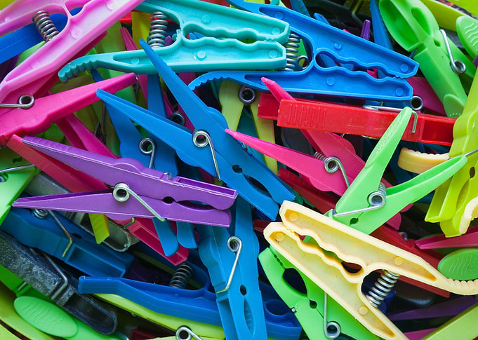 A jumble of various old plastic clothes pegs