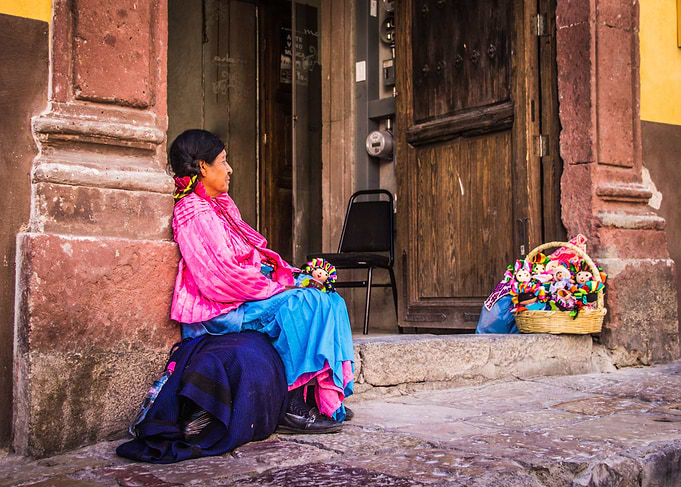 Woman with traditional mexican dress selling dolls