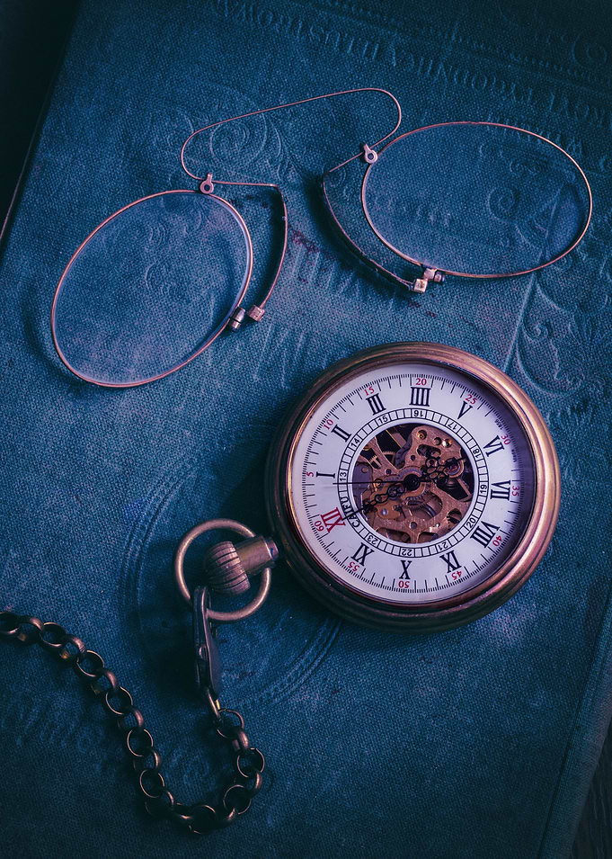 Vintage binocle and old pocket watch on blue book
