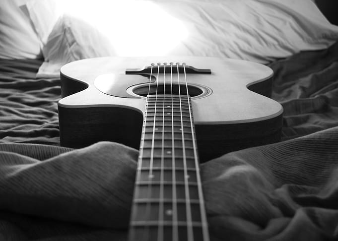 Acoustic Guitar on a Bed