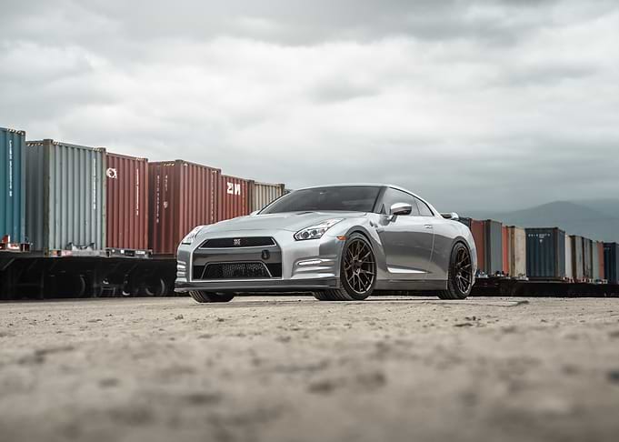Silver Nissan GTR R35 next to freight train cars