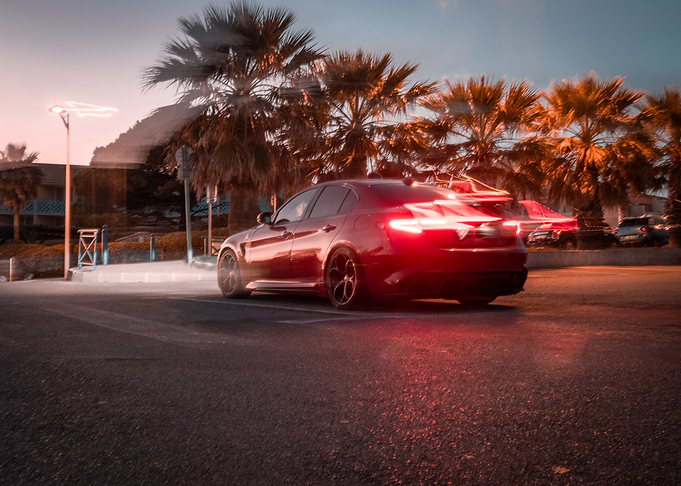 Red Sedan Under Palm Trees