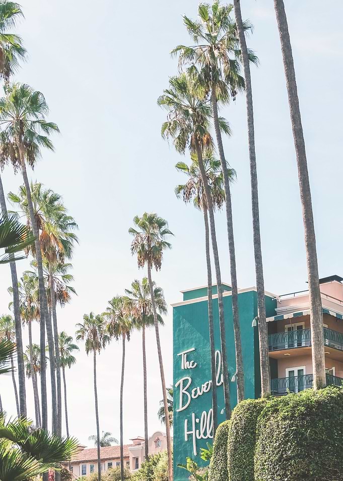 Los Angeles, USA I Green midcentury architecture of Beverly Hills Hotel under LA sun and palm trees with retro vintage summer pastel aesthetic of a film camera just like in the 1960s Hollywood movies