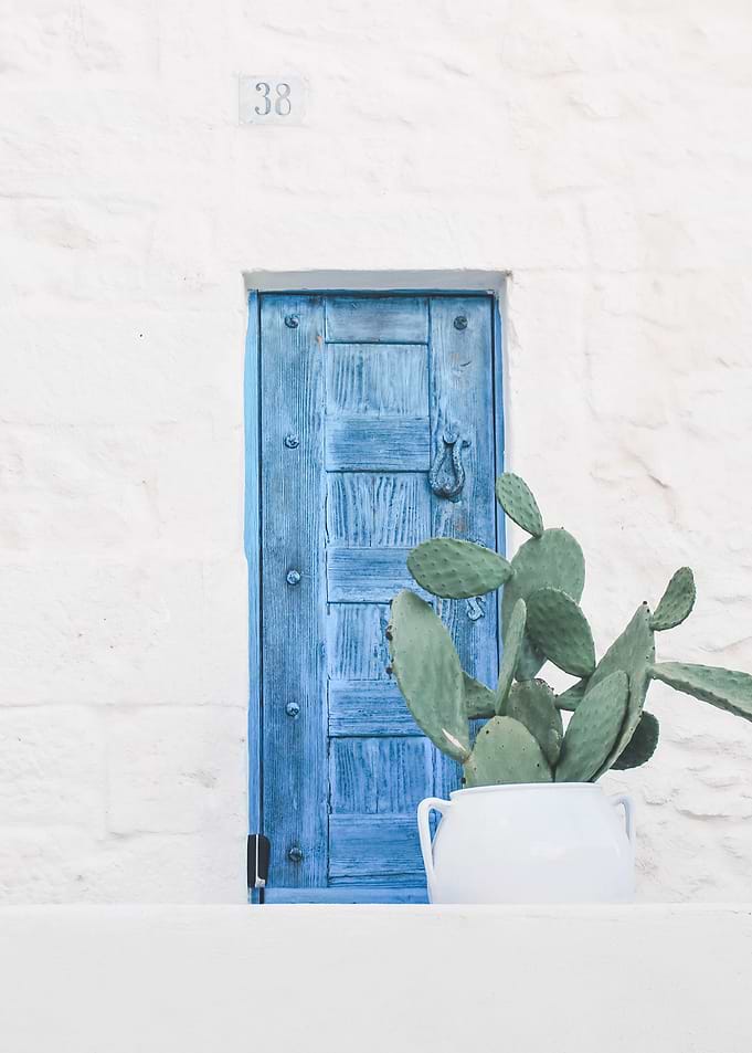 Puglia, Italy I The minimalist blue door and boho cactus in authentic Mediterranean Ostuni village on a geometric white wall with a retro vintage aesthetic during the Italian Indian pastel summer