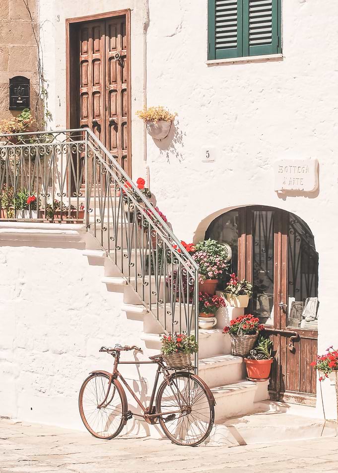 Puglia, Italy I Bicycle in front of flower house in white village of Ostuni in Italian countryside authentic retro vintage minimalist aesthetic in pastel Mediterranean summer colors during sunrise