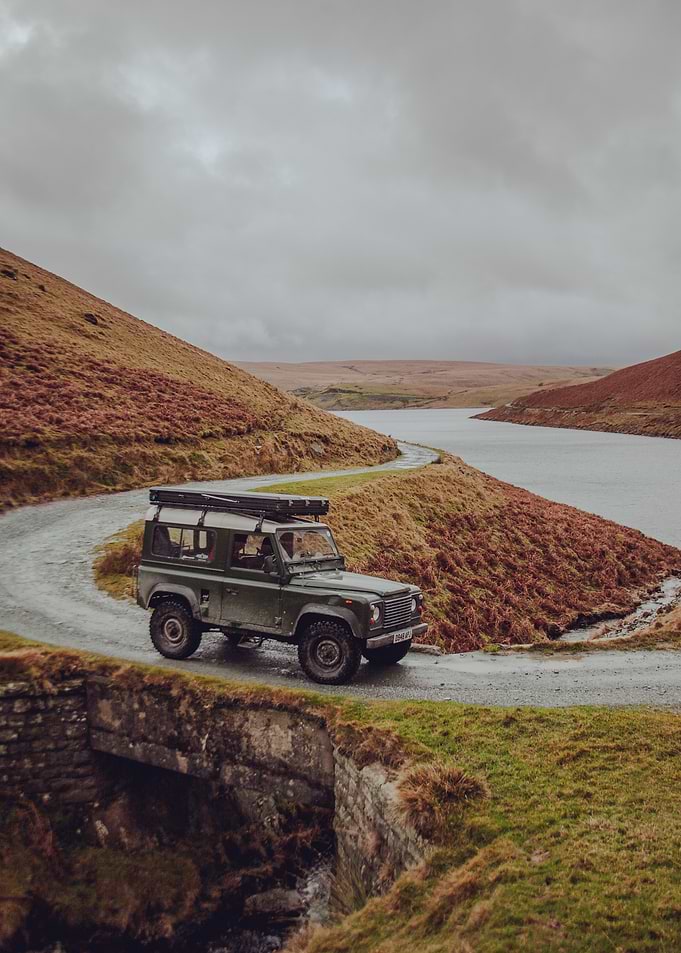 Green Land Rover Defender on Winding Road
