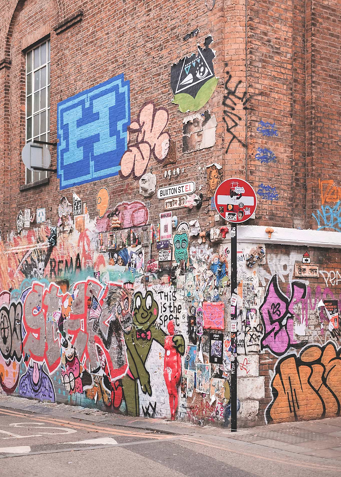 London, England I Colorful retro street art and urban graffiti on brick wall of Shoreditch streets with the industrial architecture and mural design vibrancy of London's suburbs urban exploration