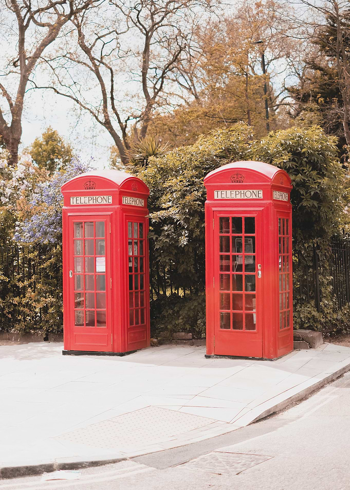 London, England I Iconic vibrant red British telephone boxes in Primrose Hill londoner district street photography of an urban scene in a natural park with autumn pastel retro vintage aesthetic