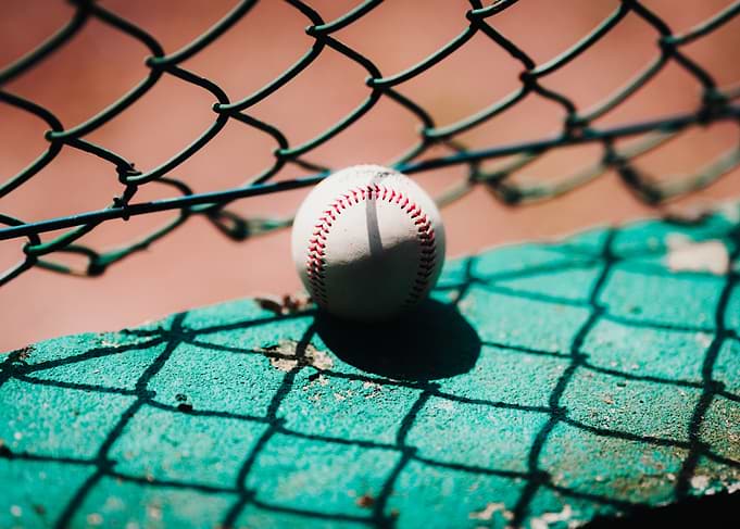Baseball on Green Surface with Fence