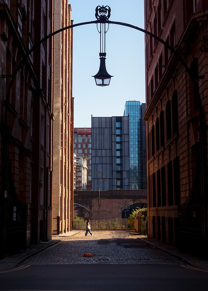 Urban alleyway with pedestrian and lamp