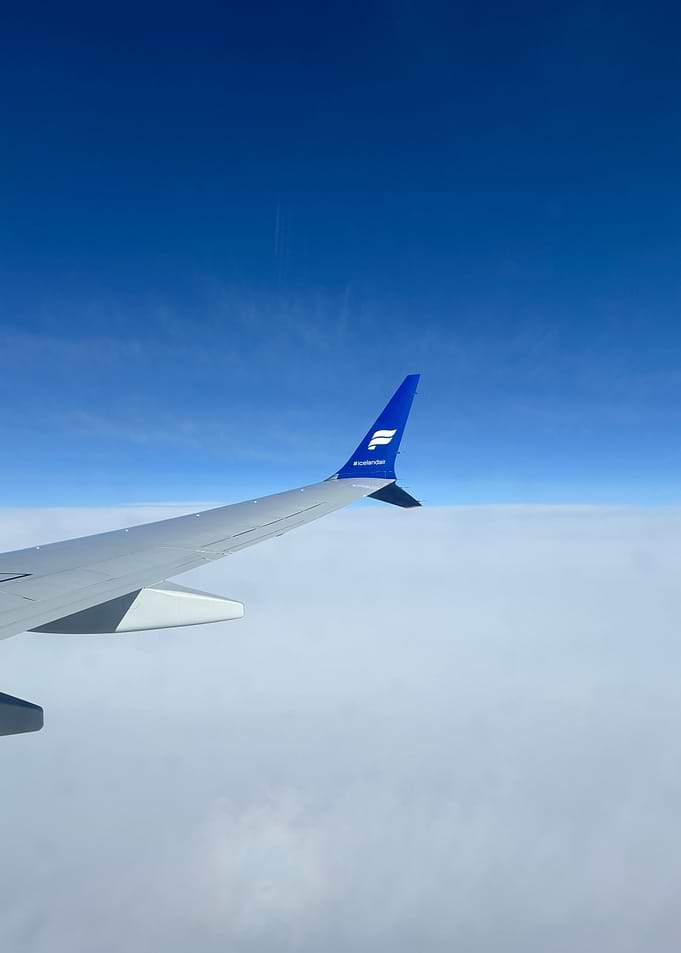 Airplane wing above clouds, blue sky