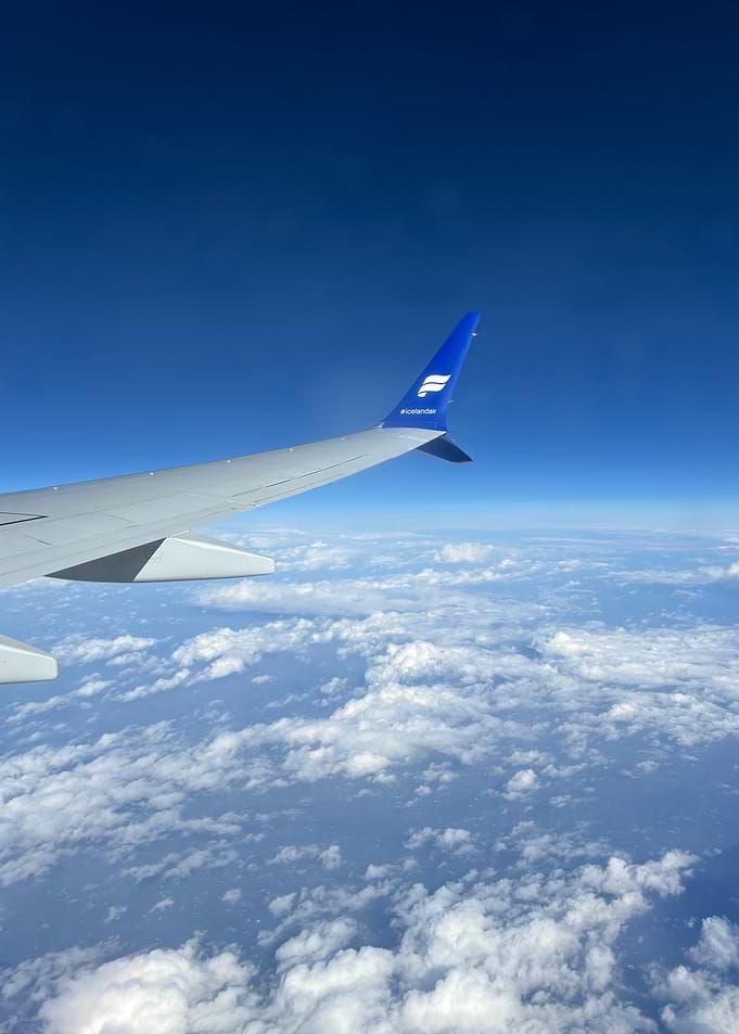 Airplane wing over clouds and sky