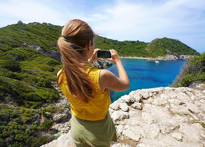 Woman taking photo of coastal view in Corfu, Greece