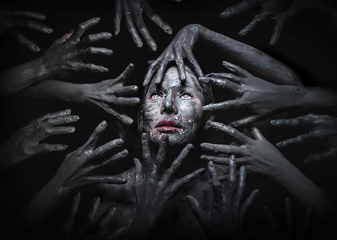 Woman surrounded by dark hands